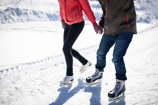 Caucasian couple ice skating on snowy frozen lake