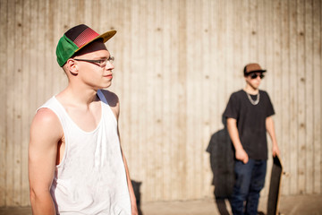 Caucasian men with skateboards near wooden wall
