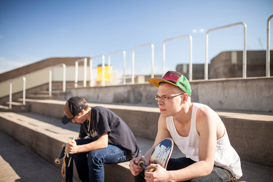 Caucasian men with skateboards sitting on steps