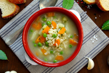 Dieting soup with vegetables and rice on wooden background. Top view with copy space. Vegetarian and vegan food.