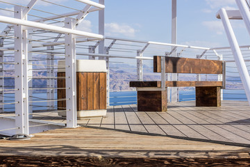 hotel high terrace observation point view on roof with wooden bench and white iron metal fence construction for safety, exterior design 