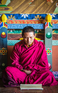 Asian monk reading on temple floor