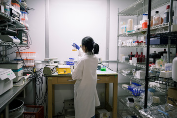 Asian scientist examining fluid in beaker