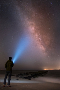 Asian Man Shining Flashlight On Starry Sky