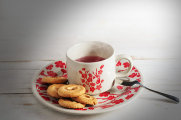 Beautiful cherry blossoms porcelain tea cup with cookies and a spoon on top of a wooden table and white background