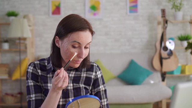 young woman with a scar on the face makes the makeup