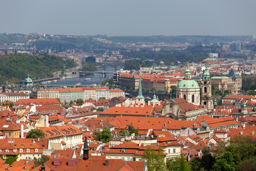 Fototapeta na wymiar Spring Prague City with St. Nicholas' Cathedral and green Nature with flowering Trees from the Hill Petrin, Czech Republic