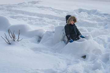 Fototapeta na wymiar Little boy sitting in a deep snow