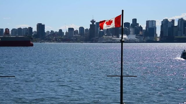 The Canadian flag waving in the sky, with the Harbour Tower visible in the background. The focus is on downtown. Seabus coming out from north to south.Ver.1
