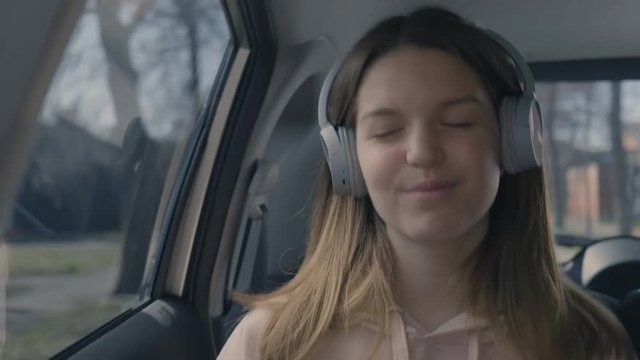 Teen girl wearing headphones and singing along while driving
