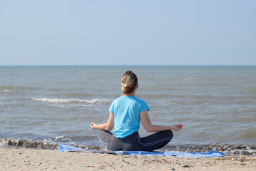 girl practices yoga by the sea. Exercise gymnastics in the fresh air by the sea.