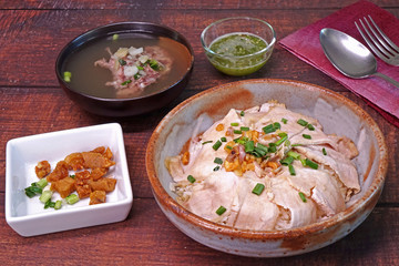 Slice grilled pork with rice, topping with fried pork rinds, pickled garlic and spring onions served with pork spare ribs soup and green spicy chili sauce. Famous Chinese / Cantonese cuisine.