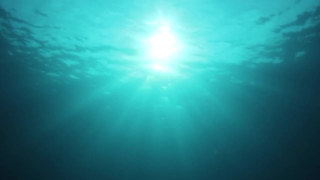 Underwater background video of sunburst on ocean surface with sunbeams