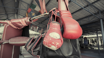 A pair of old Muay Thai boxing gloves hangs on the boxing ring at training  camp