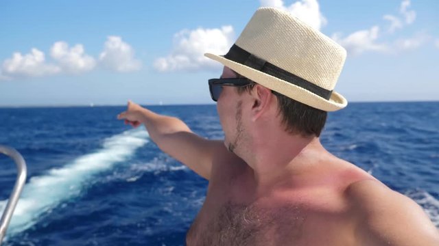 Portrait young man in hat taking selfie video on catamaran yacht with caribbean sea water background. Summer holidays. Travel vacation