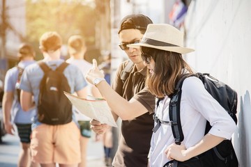 Asian backpack couple tourist holding city map crossing the road - travel people vacation lifestyle concept