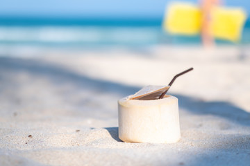 Closeup image of a fresh coconut on the beach with blue sea background