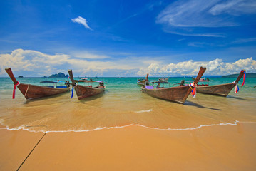 Thai traditional wooden longtail boat with beautiful sand beach and colorful cloudy blue sky...
