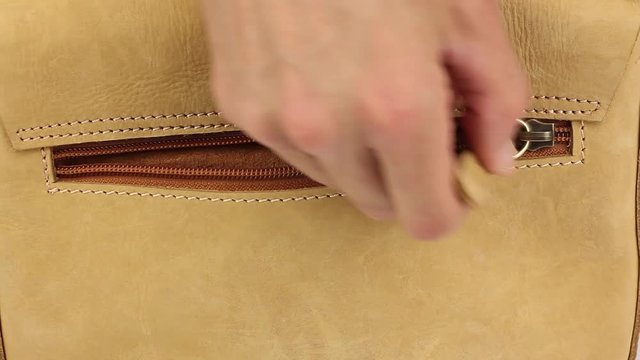 human hand opens hidden zippered pocket on bag made from natural yellow leather, then  puts his hand in pocket, then close it