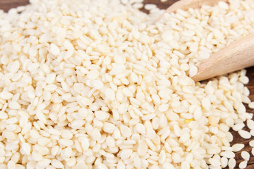Heap of sesame seeds with wooden scoop