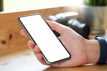 Mockup image of woman's hands holding mobile phone with blank screen in modern cafe