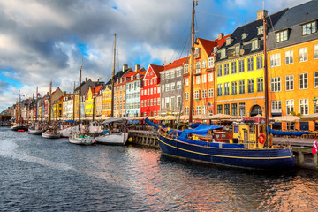 Nyhavn area of popular bar and restaurant at beautiful blue sky, with colorful facades of old houses and old ships in the Old Town of Copenhagen, capital of Denmark.