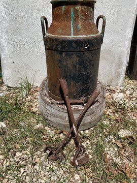 recipiente lechero de metal y fierros para marcar ganado.