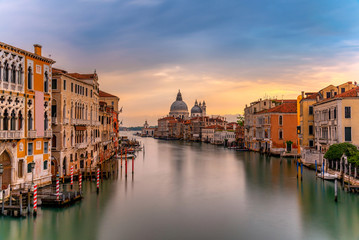 Fototapeta na wymiar Beautiful landscape sunset view of traditional Gondolas on famous Canal Grande with historic Basilica di Santa Maria della Salute in the background in romantic golden evening light at sunset in Venice