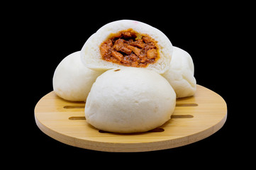 Steamed buns with red pork filling on a wooden tray and a black background