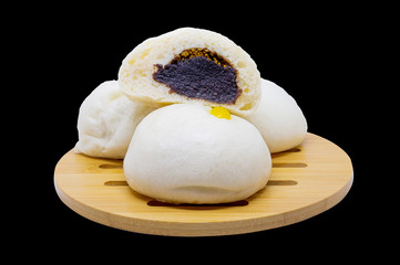 Steamed buns with black bean paste placed on a wooden tray and a black background