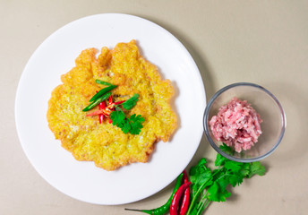 Omelette, pork chops in a white dish and with minced pork, red pepper, green coriander, placed beside the plate top view