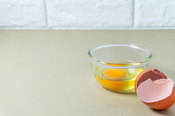 Cracked whole chicken eggs in a clear glass cup on the kitchen floor