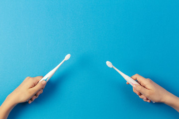 Kid hands with electric toothbrushes on blue background