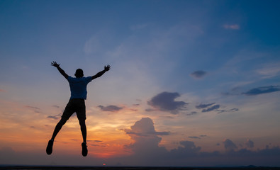 Fototapeta na wymiar Happy man jumping for joy on the peak of the mountain, cliff at sunset. Success, winner, happiness
