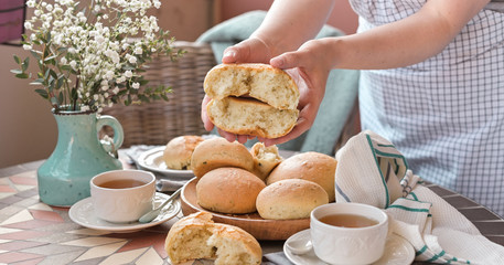 Homemade burger buns with basil in a woman's hand. Served Table for breakfast and tea. Lifestyle photo
