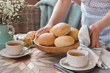 Homemade burger buns with basil in a woman's hand. Served Table for breakfast and tea. Lifestyle photo