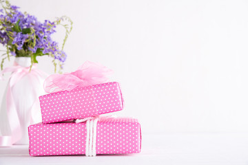 Happy mothers day concept. Gift box with purple flower on white wooden table background.