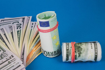 several wads of money of different currencies on a blue background.