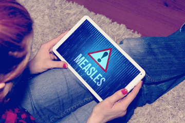 Eine Frau mit Tablet PC und Warnung vor der Masern Krankheut