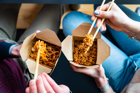 Couple Eating Food Packed In Take-away Box With Chopsticks