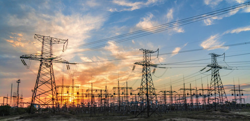 high-voltage lines against the background of electrical distribution stations at sunrise.