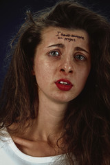 Portrait of young woman with mental health problems. Tattoo on the forehead with the words I have anorexia-I'm perfect. Concept of hidding the true feelings, psycological trouble, treatment.
