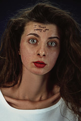 Portrait of young woman with mental health problems. The image of the tattoo on the forehead with the words I trust nobody-you. Concept of hidding the true feelings, psycological trouble, treatment.