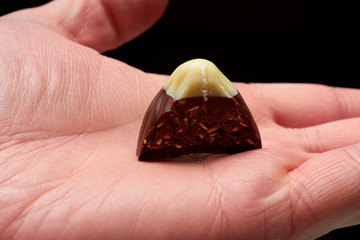 Bitten candy in hand on black background