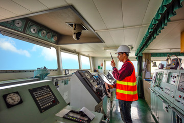 duty officer in charge handle of the ship navigating to the port destination, keep watching navigation on the bridge of the ship vessel under voyage sailing to the sea - obrazy, fototapety, plakaty