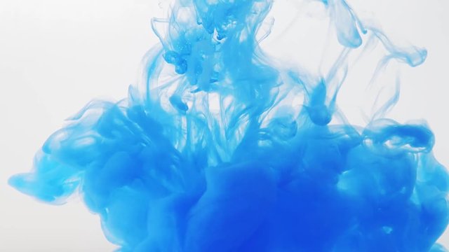 Drop of blue paint in water, close shot. Blurred background. Ink dissolving into water, abstract background. Abstract acrylic clouds in liquid. Droplet of blue ink disappearing in liquid