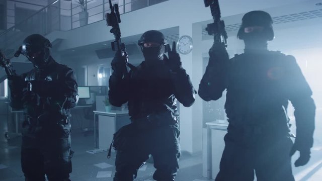 Masked Team of Armed SWAT Police Officers with Rifles are Posing After a Successful Office Building Siege. Soldiers Stand in a Row and Raise Firearms Up in the Air.