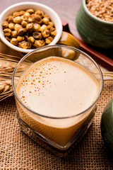 Sattu sharbat is a cooling sweet drink made in summer with roasted black chickpea flour, barley, suger, salt & water. served in a glass. selective focus