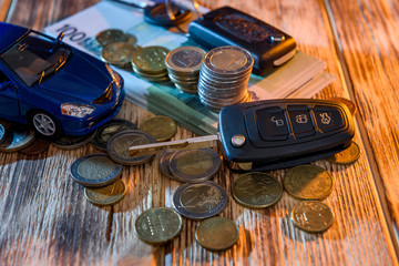 Key from car and toy car at euro banknotes with coins