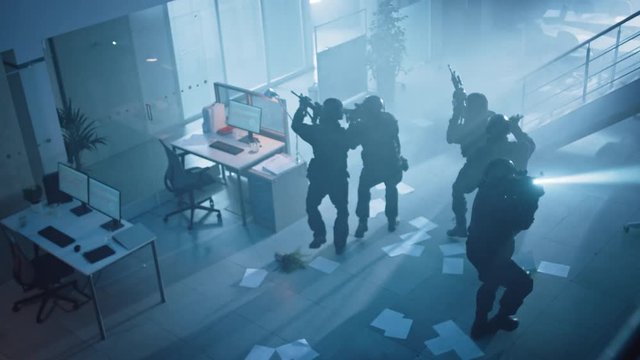 Masked Team of Armed SWAT Police Officers Slowly Move in a Hall of a Dark Seized Office Building with Desks and Computers. Soldiers with Rifles, Flashlights Surveil and Cover Surroundings. Above View.